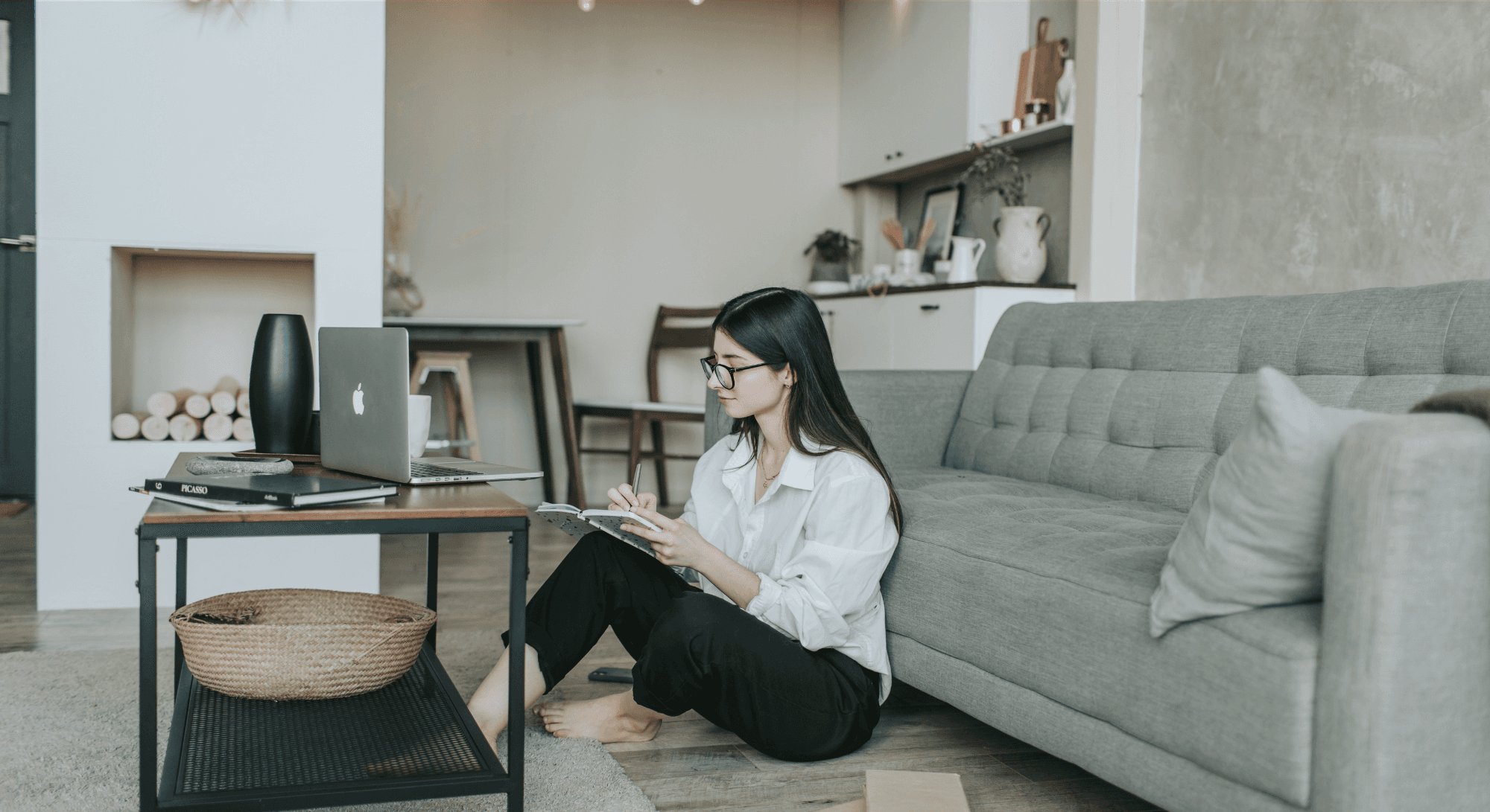 A womn taking note while looking at a laptop.png